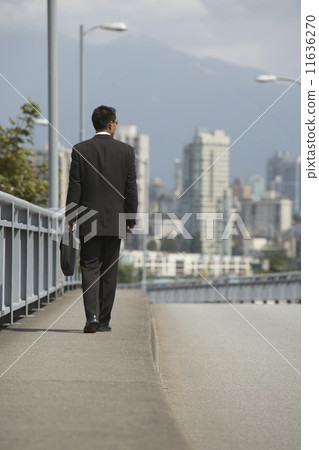 Asian businessman walking on urban bridge 11636270