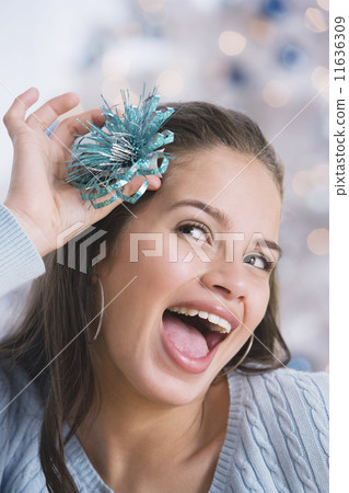 Hispanic teenaged girl holding bow in hair Hispanic teenaged girl holding bow in hair 11636309