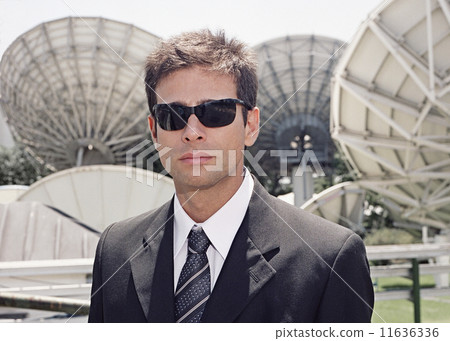 Hispanic businessman in front of satellite dishes Hispanic businessman in front of satellite dishes 11636336