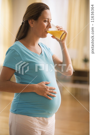 Pregnant woman drinking a glass of juice Pregnant woman drinking a glass of juice 11636364