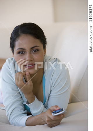 Young woman pointing remote control 11636371