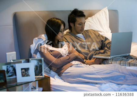 Asian couple looking at laptop Asian couple looking at laptop 11636388