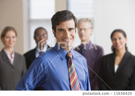 Businessman standing with coworkers in the background Businessman standing with coworkers in the background 11636420