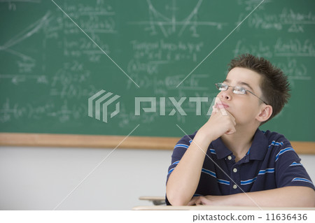 Hispanic boy thinking at school desk 11636436