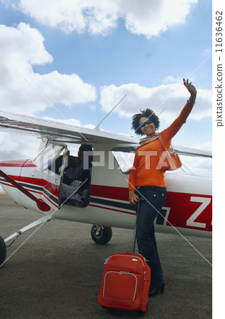 African woman with suitcase next to airplane 11636462