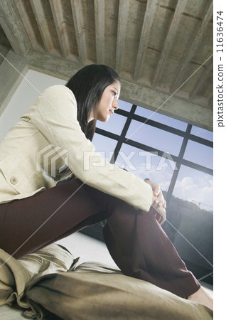 Hispanic woman sitting with hands on knees 11636474
