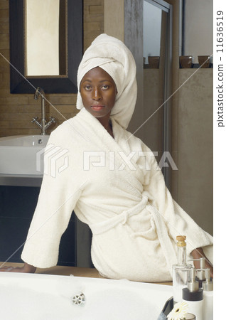 African American woman in bathroom wearing bathrobe 11636519