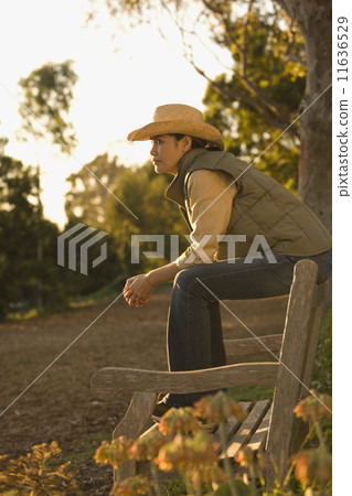 Asian woman sitting on park bench 11636529