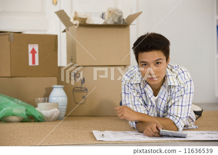 Asian man next to unpacked moving boxes Asian man next to unpacked moving boxes 11636539