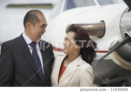 Asian businesspeople laughing next to airplane 11636609