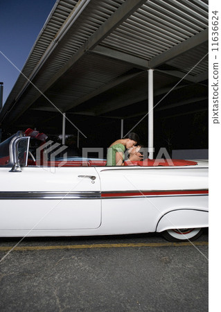 Multi-ethnic couple kissing in convertible 11636624