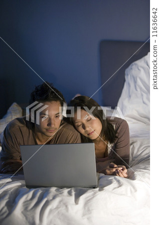 Asian couple looking at laptop Asian couple looking at laptop 11636642
