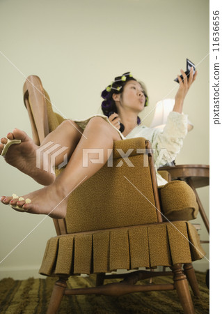 Asian woman in curlers looking in mirror 11636656