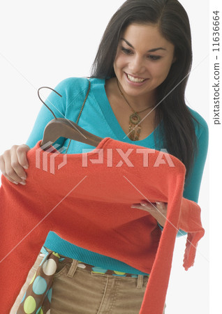 Teenage girl looking at sweater and smiling Teenage girl looking at sweater and smiling 11636664