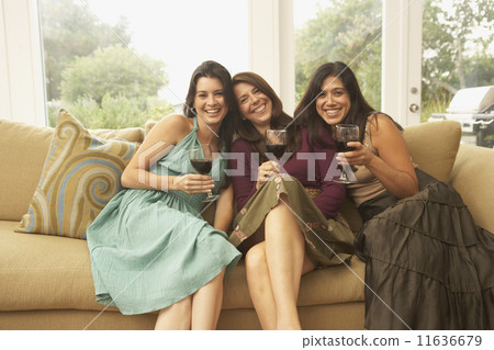 Portrait of three women sitting on couch with wine glasses 11636679