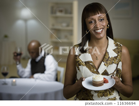 African woman holding plate of dessert 11636694
