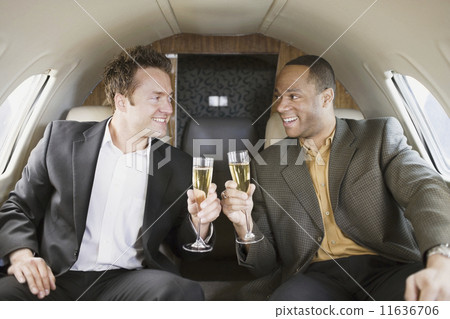 Multi-ethnic businessmen toasting on airplane Multi-ethnic businessmen toasting on airplane 11636706