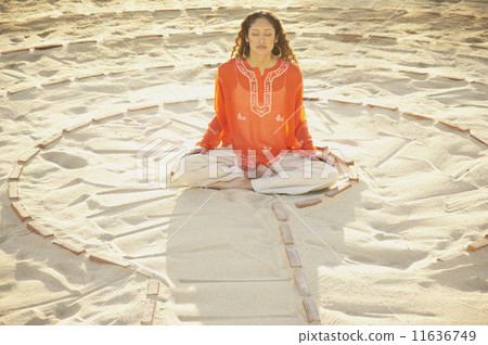 Woman sitting cross-legged in the middle of a meditation labyrinth 11636749