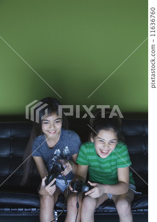 Two girls playing video game on sofa 11636760