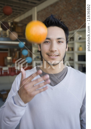 Asian man tossing fruit in air Asian man tossing fruit in air 11636802