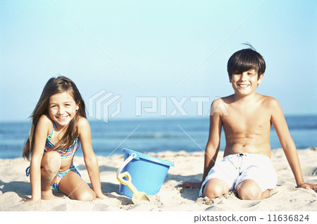 Brother and sister play in the sand at the beach 11636824