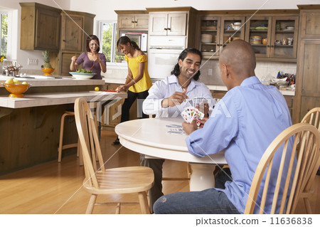 Multi-ethnic couples preparing dinner and playing cards 11636838