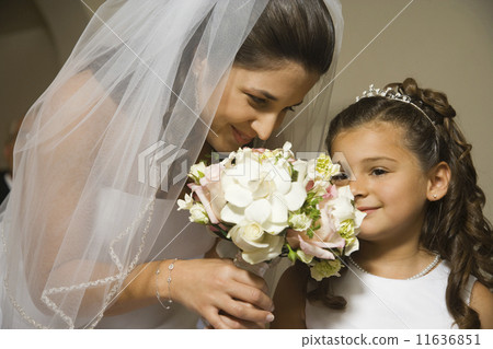 Hispanic bride and young girl smelling flowers Hispanic bride and young girl smelling flowers 11636851