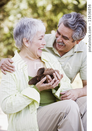 Middle-aged couple with handful of pinecones outdoors 11636856