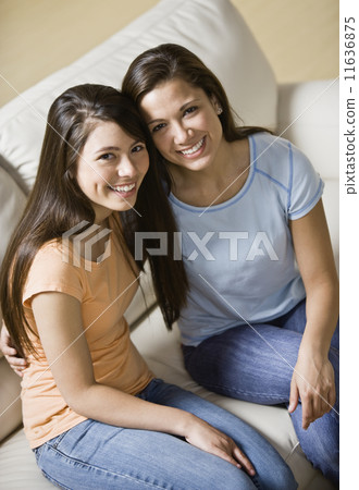Asian sisters sitting on sofa 11636875