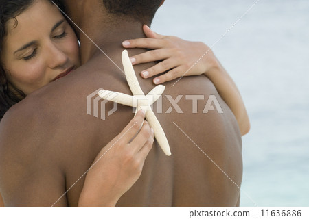 Hispanic couple hugging with starfish Hispanic couple hugging with starfish 11636886