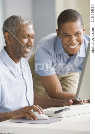 African American father and adult son looking at computer African American father and adult son looking at computer 11636939
