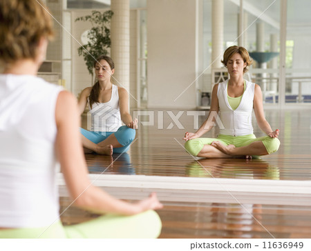 Two Hispanic women meditating at health club Two Hispanic women meditating at health club 11636949