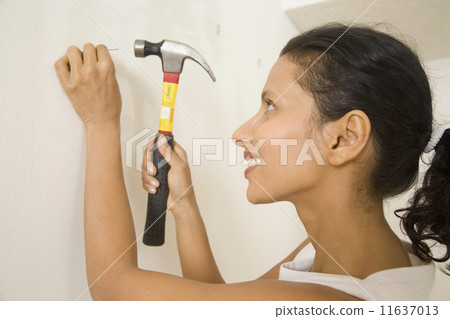 Indian woman hammering nail into wall Indian woman hammering nail into wall 11637013