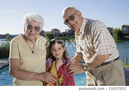 Hispanic grandparents and granddaughter next to swimming pool 11637052