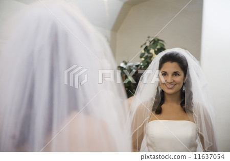 Hispanic bride looking in mirror 11637054