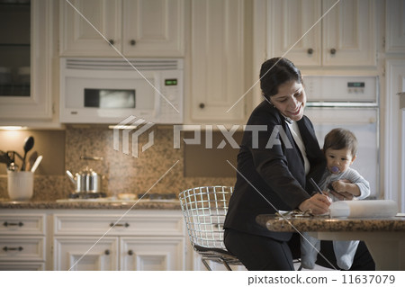 Hispanic mother on cell phone holding baby 11637079