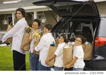 Hispanic family unloading grocery bags from car 11637094
