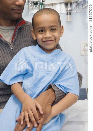 African boy in hospital gown sitting on father's lap 11637096