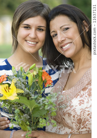 Hispanic mother and daughter holding flowers 11637131