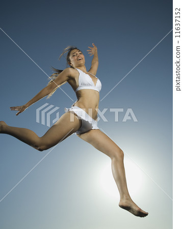 Asian woman in bathing suit jumping 11637152