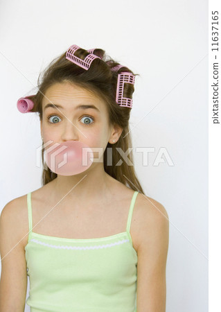 Studio shot of young girl with curlers blowing bubble gum Studio shot of young girl with curlers blowing bubble gum 11637165