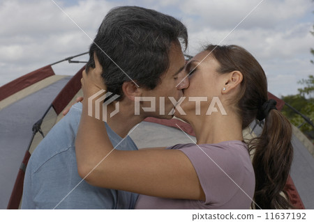 Hispanic couple kissing in front of tent 11637192