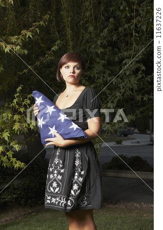 Mixed Race woman holding folded American flag 11637226