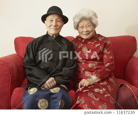 Senior Asian couple in traditional dress on sofa 11637230