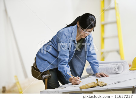 Hispanic woman looking at blueprints Hispanic woman looking at blueprints 11637237