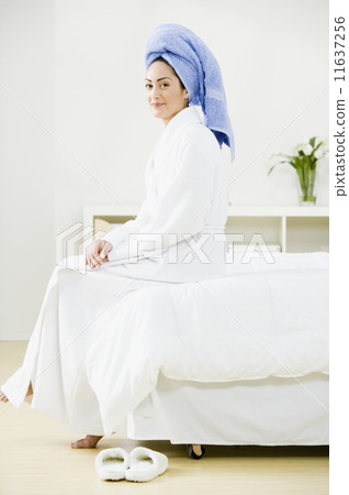 Hispanic woman sitting on edge of bed 11637256