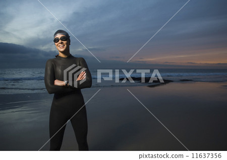 Hispanic woman in wetsuit on beach Hispanic woman in wetsuit on beach 11637356
