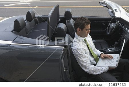 Businessman working on laptop while sitting in convertible 11637383
