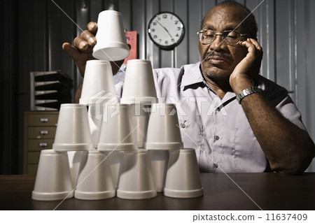 Senior African American male worker stacking cups 11637409