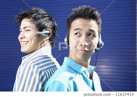 Two young men back to back wearing headsets Two young men back to back wearing headsets 11637414